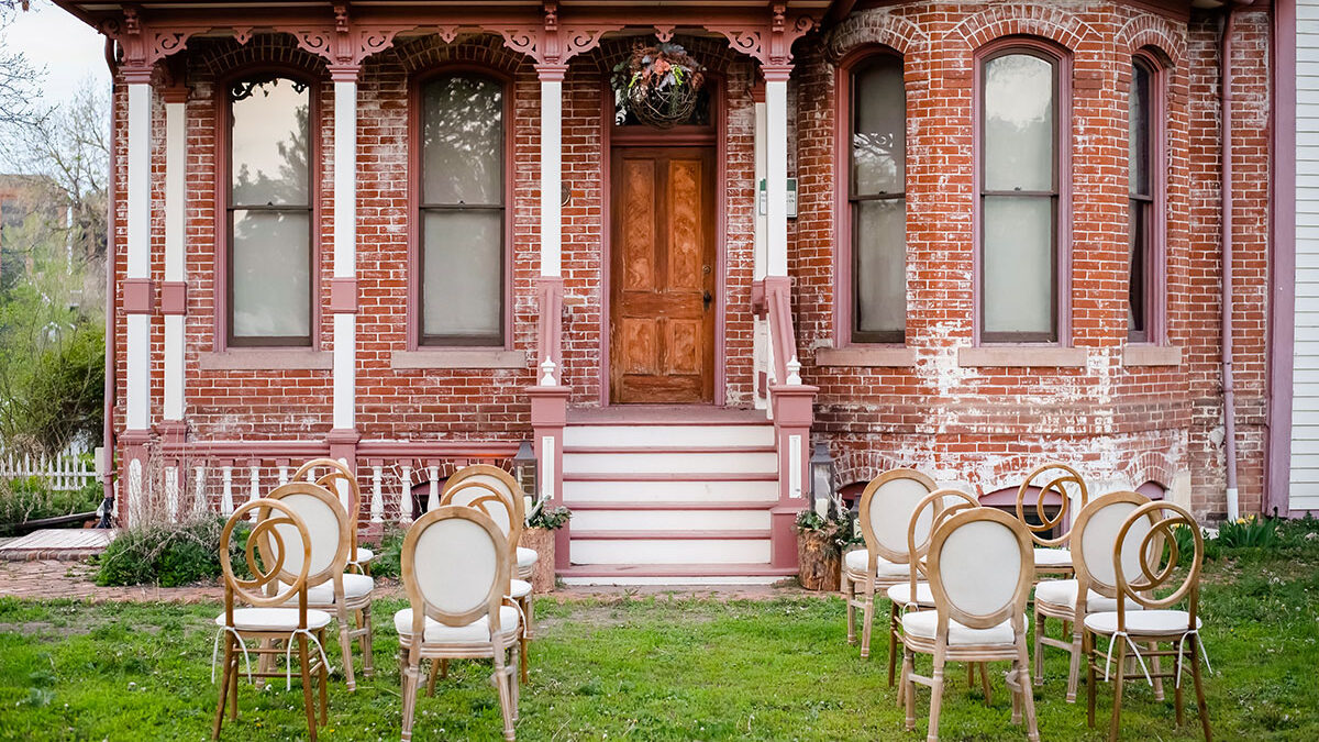 Vintage house with arched windows, pink trim, and circular chairs arranged on the lawn