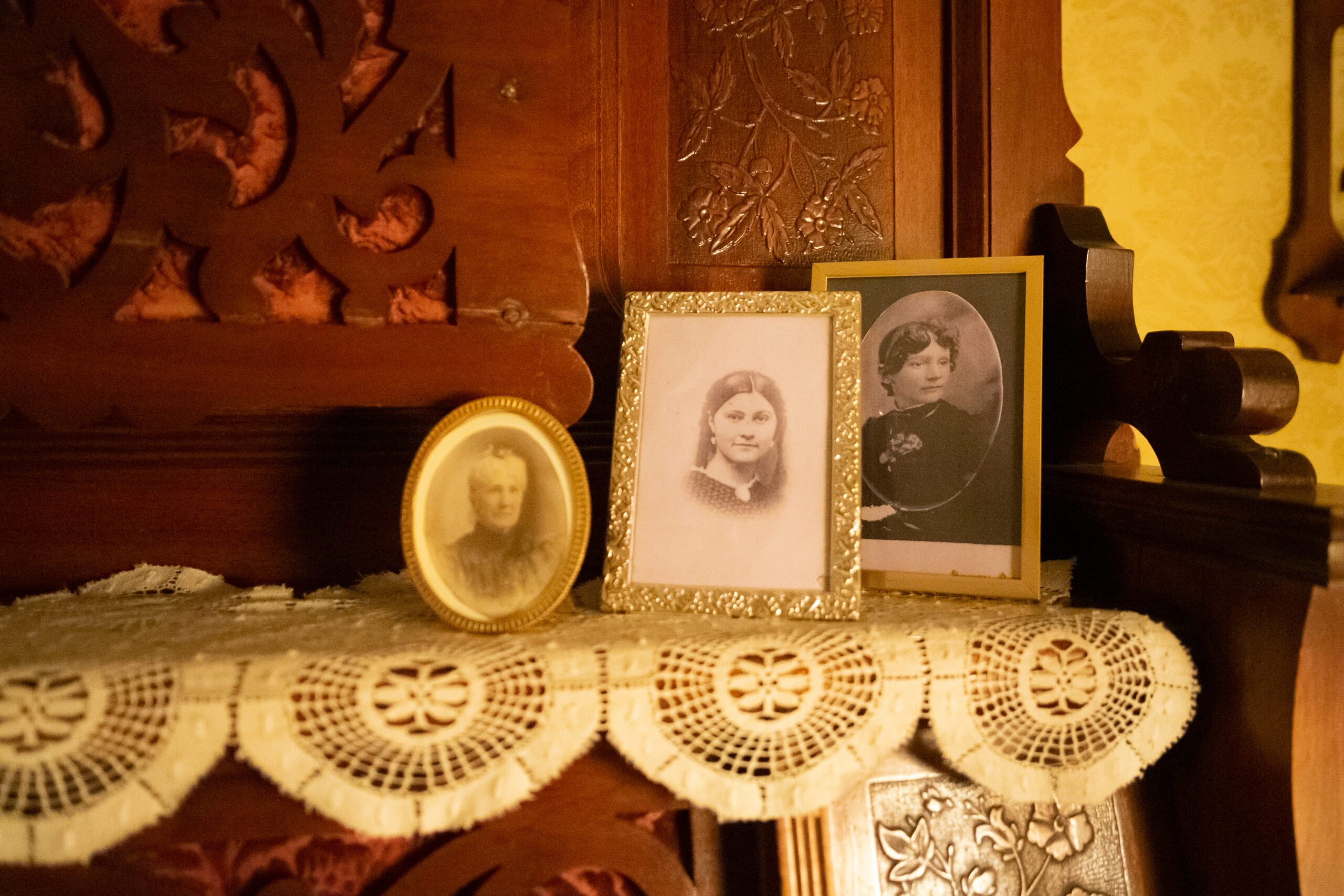 Vintage photographs of three women in ornate frames on lace doily