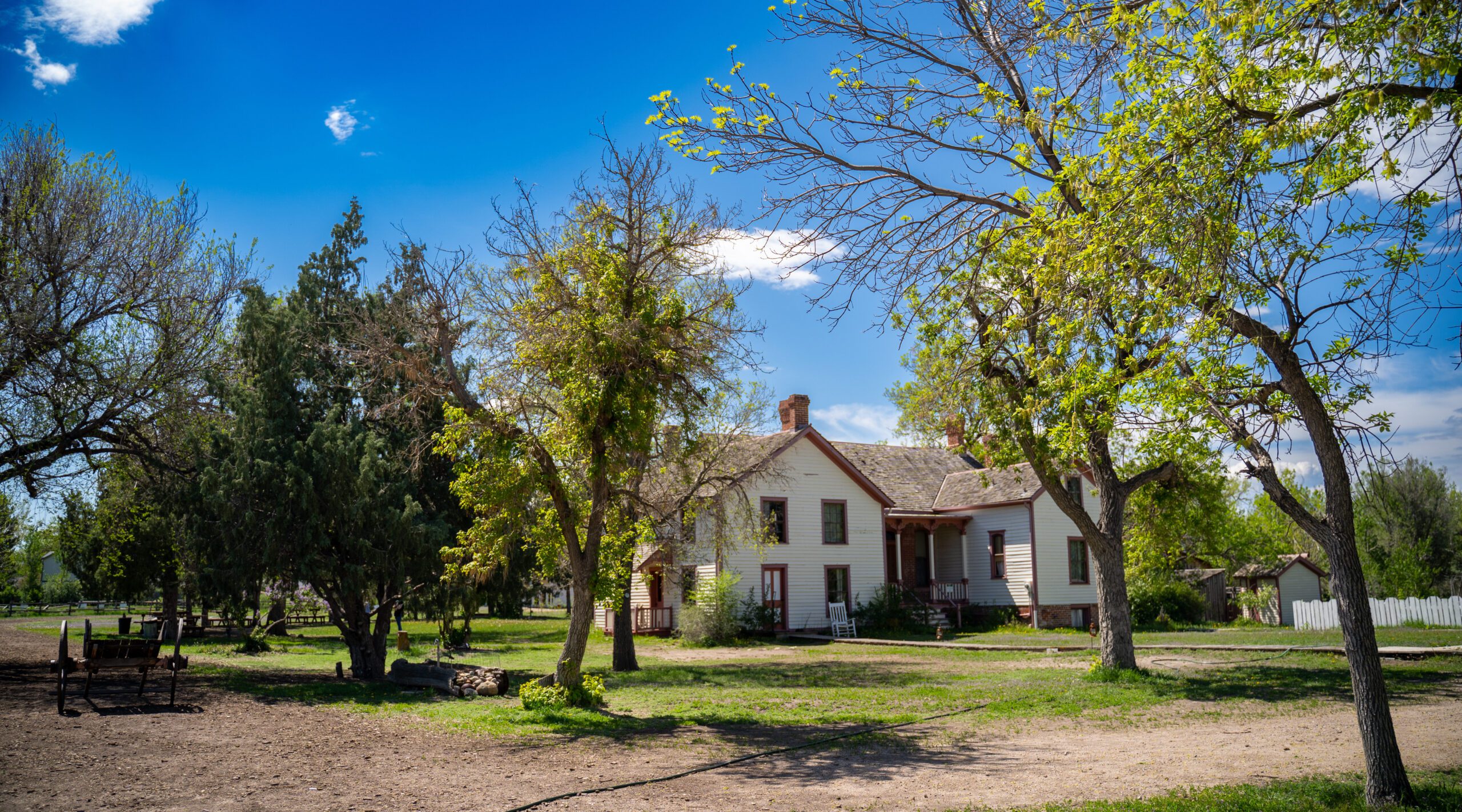 Historic farmhouse in a sunny rural setting surrounded by trees
